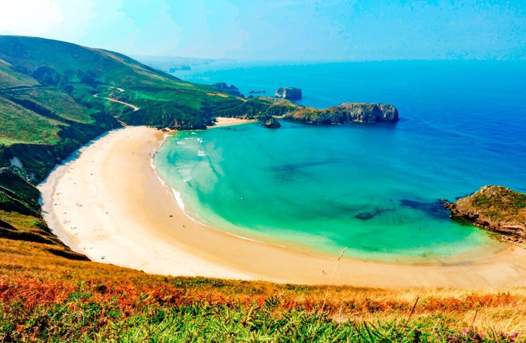 A breathtaking panoramic view of Playa de Torimbia in Asturias, Spain, showing its iconic half-moon shell shape, turquoise Atlantic waters, and the lush green mountain cliffs surrounding the shore.